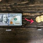 dollar bill and gold round coins on brown wooden surface