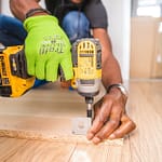 person using dewalt cordless impact driver on brown board
