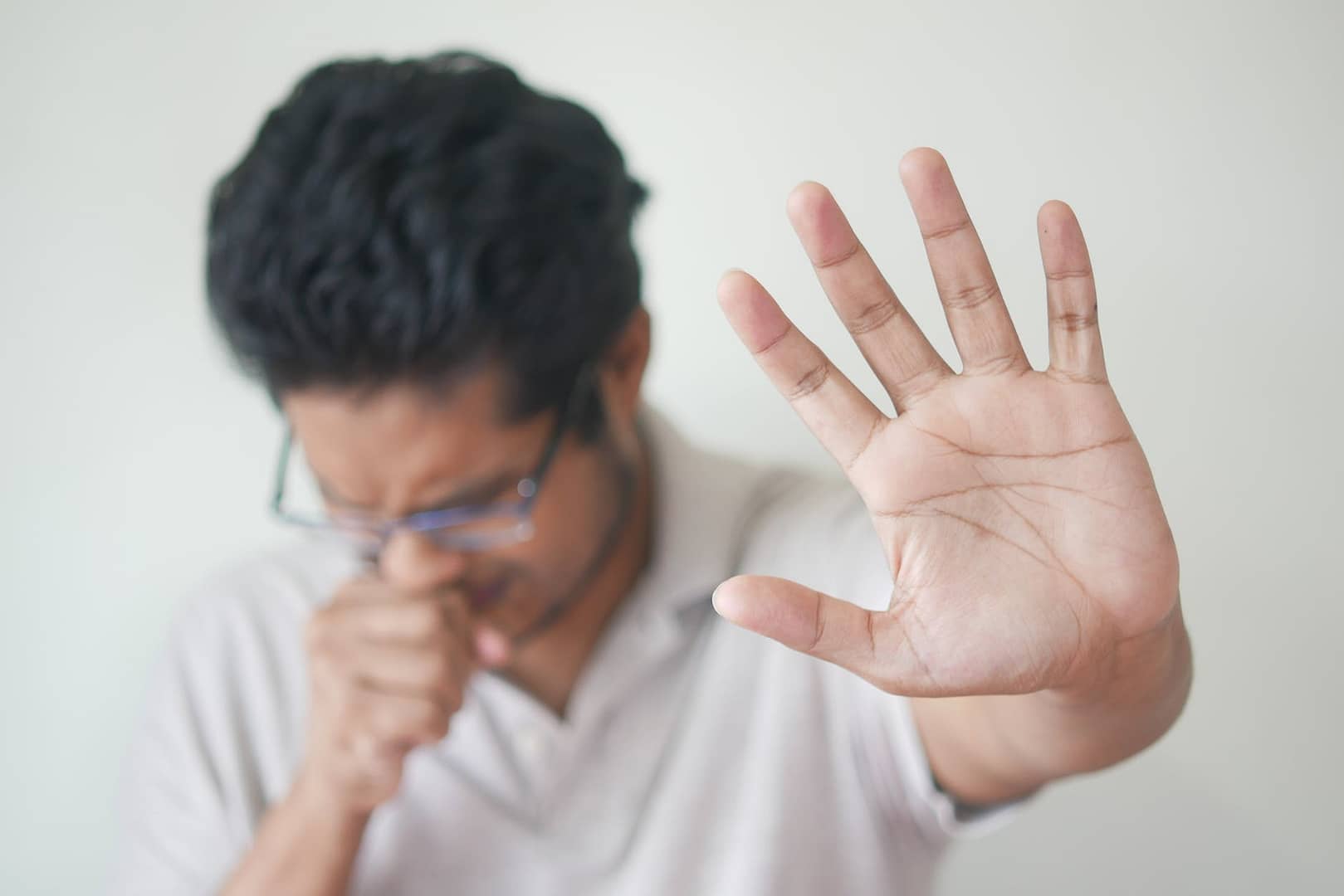 selective focus photo of coughing man s hand