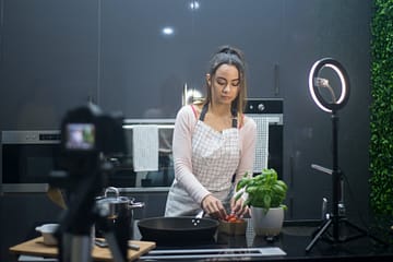 a woman cooking while blogging