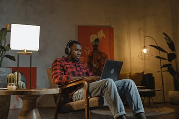 man sitting on an armchair while using his laptop
