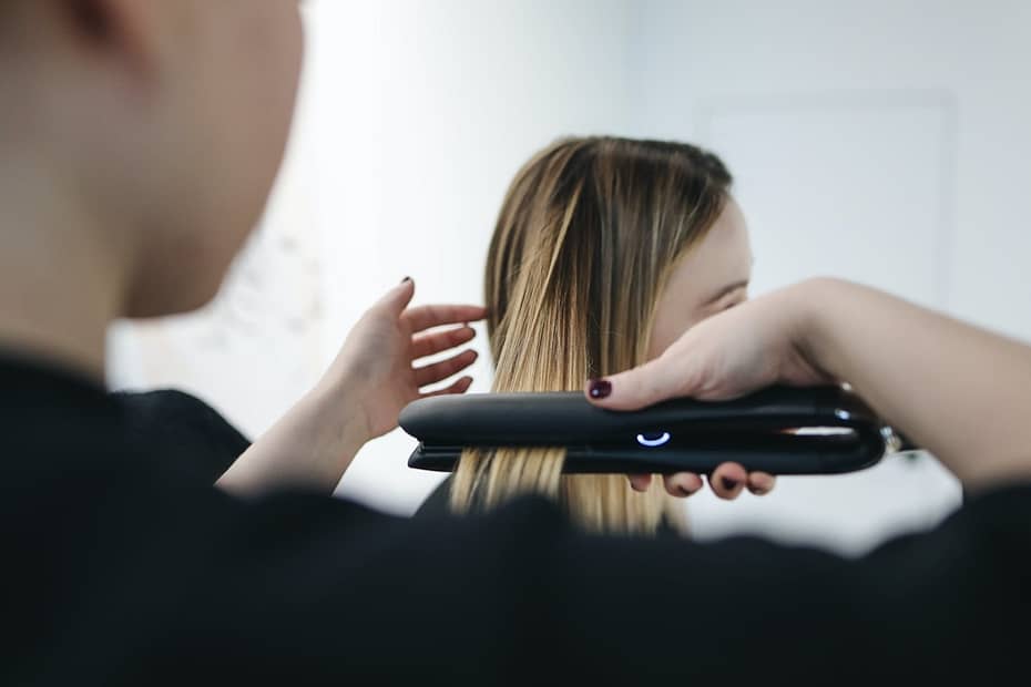 selective focus photo of person ironing a woman s hair