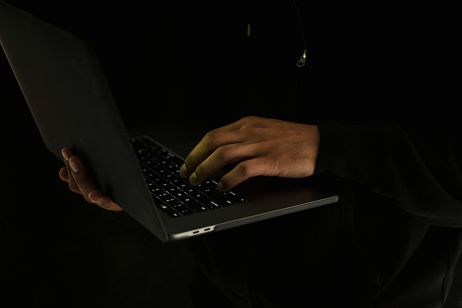 crop unrecognizable man using laptop in darkness